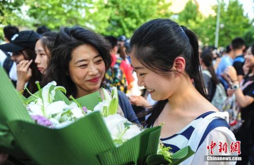 資料圖：山東濟(jì)南眾多考生手捧鮮花在家長(zhǎng)的簇?fù)硐職g快告別高考。中新社記者 張勇 攝