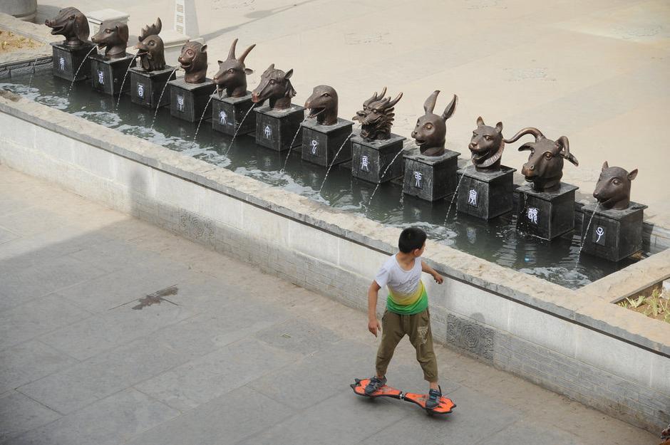 圖為一名市民從獸首旁經(jīng)過。