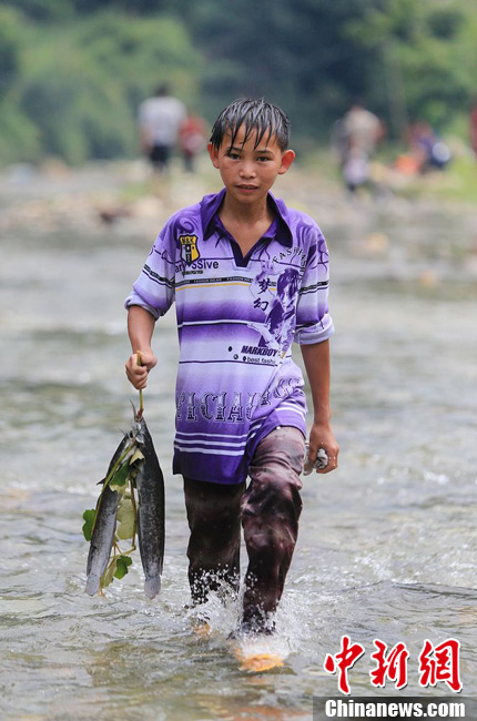 圖為7月9日，一名男孩在鬧魚節(jié)活動中抓到了兩條魚。譚凱興 攝