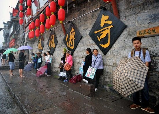 　4月29日上午11時(shí)20分，一些游客和古城當(dāng)?shù)氐木用穸阍谝粋€(gè)酒吧的屋檐下避雨。這些當(dāng)?shù)鼐用褚詾橛慰团恼罩\生，一場(chǎng)降雨讓他們的生意更加清淡。