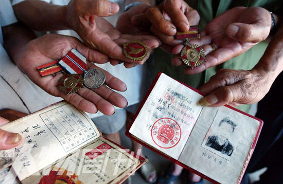幾位志愿軍老兵展示自己的立功證、傷殘軍人證與勛章