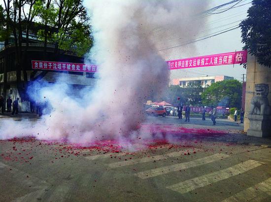 市民在普洱市主干道振興大道的金孔雀交通運(yùn)輸集團(tuán)有限公司門前燃放鞭炮，公司門前掛著“貪腐份子沈培平被查處，罪有應(yīng)得，大快人心?！钡臈l幅