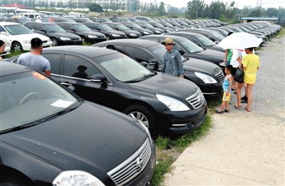 昨日，市民在山東棗莊一家拍賣公司場地上查看待拍賣公車。當(dāng)日，棗莊市103輛公車公開拍賣。新華社記者