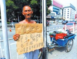 老人舉著牌子在路邊等候失主。京華時報記者譚青攝