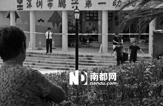 →7月19日，鵬興花園第一幼兒園門(mén)前，民警在現(xiàn)場(chǎng)進(jìn)行完勘查取證后，園長(zhǎng)和保安的尸體被運(yùn)走。南都記者 徐文閣 攝