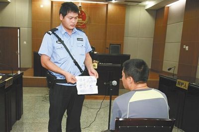 昨日庭審中，法警向趙某出示其扎完車胎后所留辱罵公司的紙條。通訊員 李秀文 攝