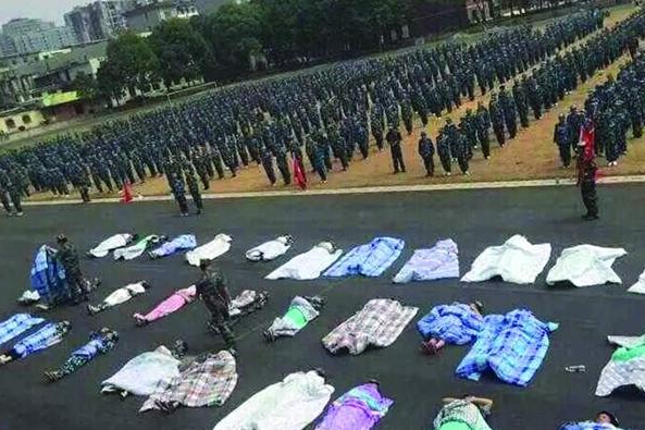 20多名女生躺在瀝青跑道上，身上嚴(yán)嚴(yán)實(shí)實(shí)地裹著棉被，接受太陽(yáng)的照曬。