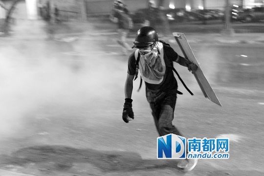 反政府示威者在與警察的沖突中躲避催淚彈。