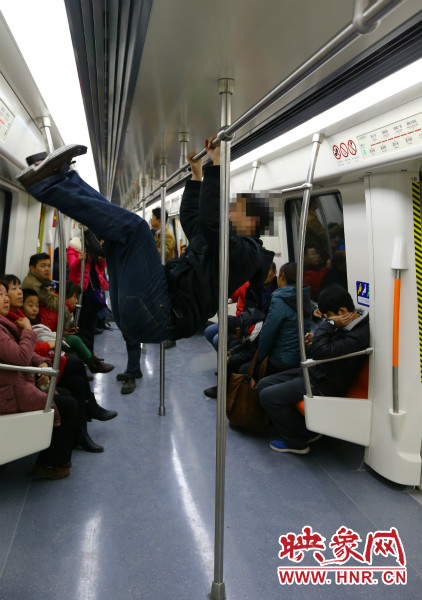 地鐵試乘日，一男子在車廂內(nèi)攀爬扶手自?shī)首詷?lè)