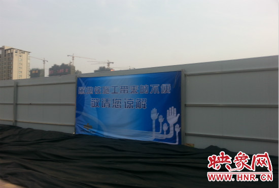 道路南側(cè)圍起了白色的圍擋，墻上標(biāo)示著“因地鐵施工帶來(lái)的不便敬請(qǐng)您諒解”的提示牌。