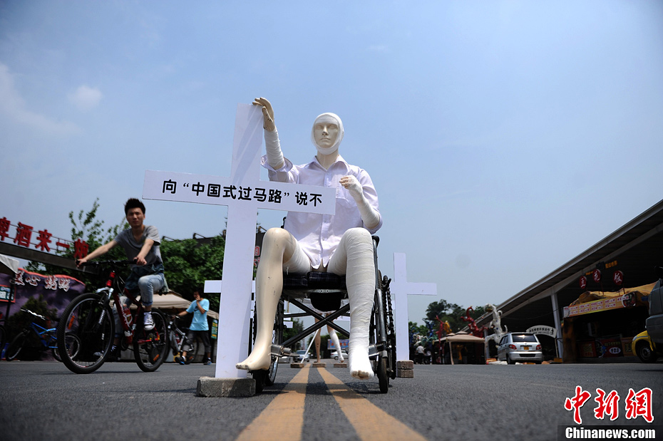 4月16日，重慶市洋人街上擺放著兩個(gè)受了傷的塑料人像“模特”，旁邊十字架上寫著向“中國式過馬路”說不