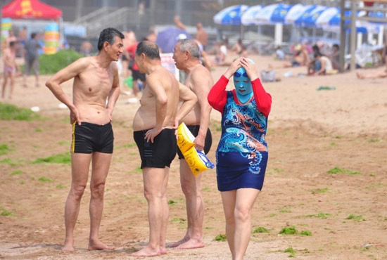 2013年7月3日，山東青島青島高溫來襲，“青島大媽”不懼滸苔，戴著“強(qiáng)盜面具”出現(xiàn)在海水浴場(chǎng)消暑降
