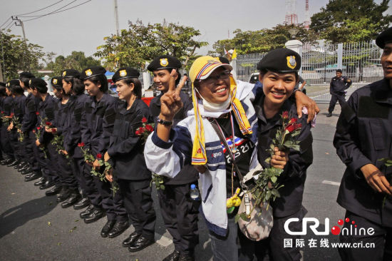 2013年12月03日,曼谷總理府與曼谷警署允許反政府示威民眾進(jìn)入,雙方進(jìn)入暫時(shí)“停戰(zhàn)”狀態(tài)迎接泰王生日。曼谷警察總署,女警們手持鮮花送給反政府示威民眾。圖片來源:Manish Swarup/東方IC