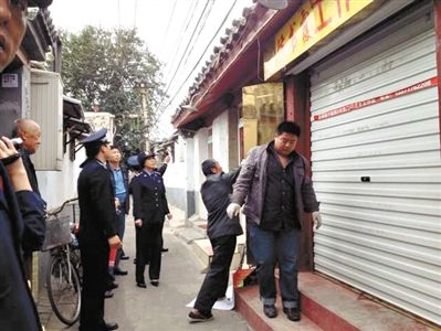 執(zhí)法人員拆除胡同里一家店面未經(jīng)審批的招牌。