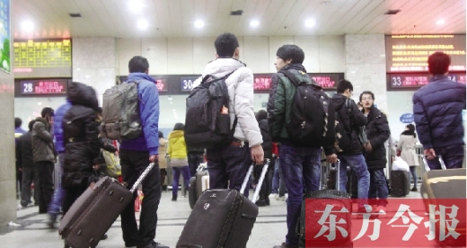 鄭州火車(chē)站東廣場(chǎng)售票大廳，幾名學(xué)生在售票窗口前躊躇