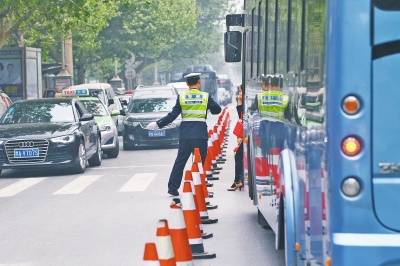 省人民醫(yī)院南門的路中間擺放反光錐，交警示意由西向東車輛從前方繞行。