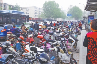 省人民醫(yī)院北門，路邊的公交站牌處停滿非機動車，上、下客只能在快車道上。