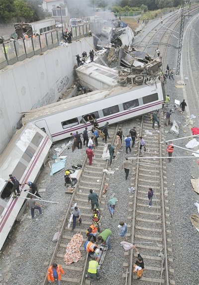 24日，救援人員在西班牙列車脫軌現(xiàn)場。一節(jié)車廂被強(qiáng)大的慣性拋上鐵道邊的高臺。