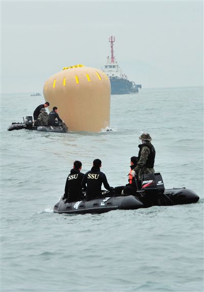 18日，搜救人員準備將氣囊捆綁到沉沒客輪上。