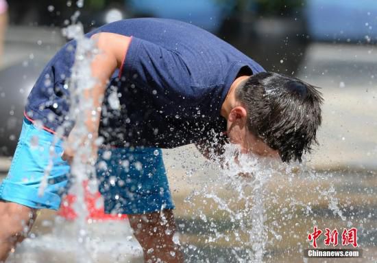 5月29日，一名小孩將頭伸向北京街頭的噴泉以降溫祛暑。