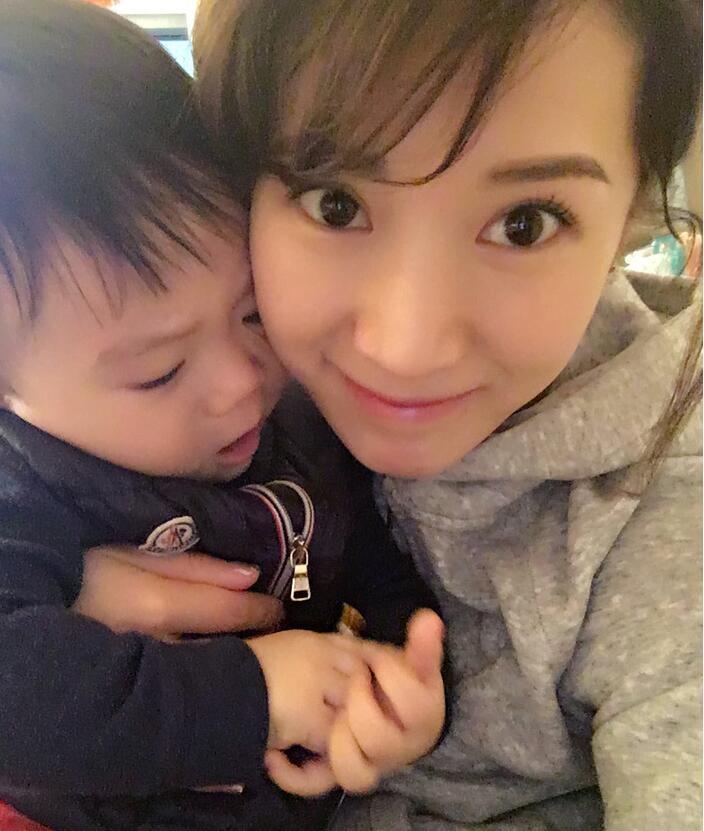 照片中李念狂吻兒子，小寶貝自顧自地玩著。