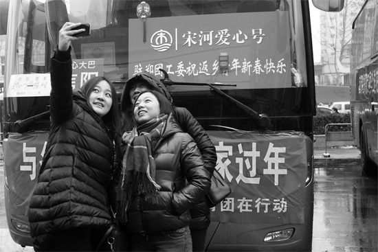 昨天上午8時，鄭州正道中環(huán)百貨廣場，準(zhǔn)備回家的老鄉(xiāng)在愛心大巴車前合影留念