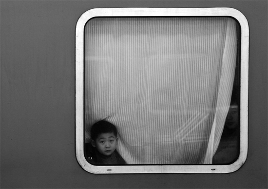 一個(gè)孩子把頭伸向窗外，他想再看送別的親人一眼