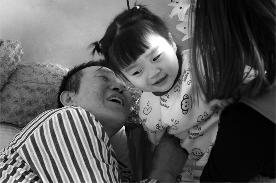 病床前李剛父女倆說著“悄悄話”，幸福的氣氛洋溢在病房中