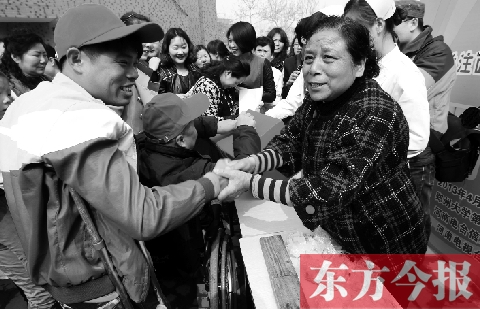 昨日，鄭大四附院的大樓前，“面人鄭”鄭玉芬（右）向前來捐款的殘疾人表示感謝