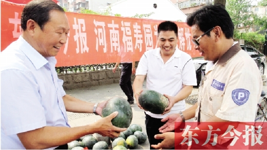 河南福壽園區(qū)域總經(jīng)理吳正宗（左一）、東方今報發(fā)行中心副總監(jiān)王路喜（中）在街頭給市民送瓜