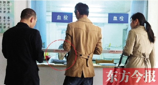 昨日，鄭州市二七區(qū)疾控中心辦證大廳，血檢窗口內(nèi)一名女工作人員，邊接受辦證者咨詢邊看報(bào)紙