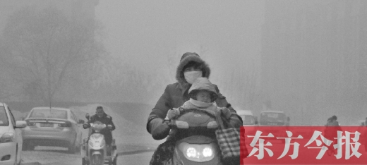 12月8日，鄭州市未來路上，一位市民帶著孩子在霧中騎行
