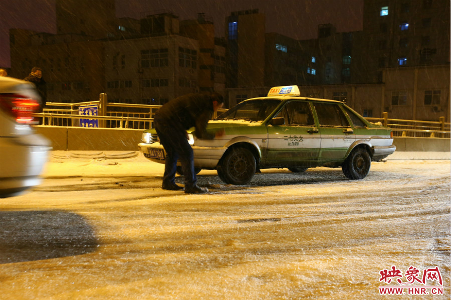 一位出租車司機(jī)在車輪前灑上雪，希望能增加輪胎的摩擦力。