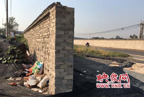 一墻之隔，一邊是道路，一邊是垃圾和荒草，市民質(zhì)疑其為遮羞墻。