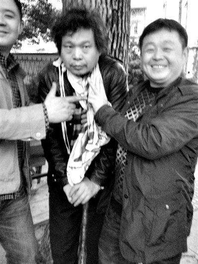 兩名接訪人員與患有癌癥的訪民段新德合影時(shí)，面帶笑容擺出勝利的手勢(shì)。