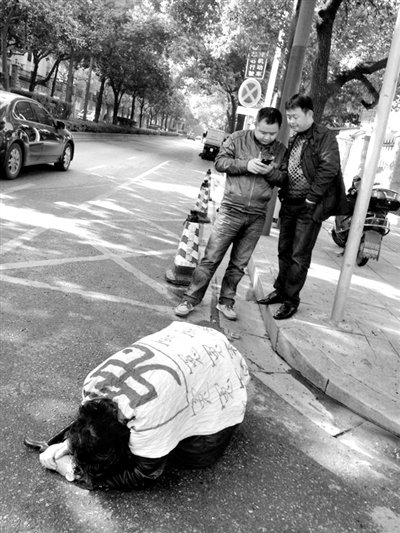 兩名接訪人員與患有癌癥的訪民段新德合影時(shí)，在拍照時(shí)查看手機(jī)。