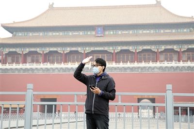 11月1日，北京大部分地區(qū)重度污染，一名游客戴著口罩在午門前揮手跟朋友打招呼。 實(shí)習(xí)生 王飛 攝