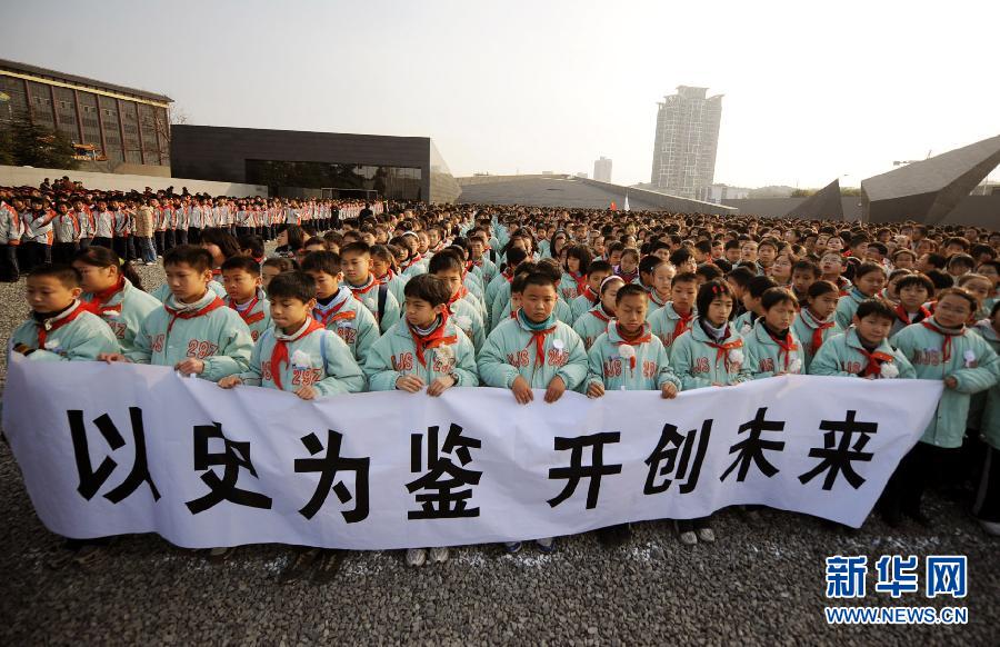 ，南京市小學(xué)生代表手持“以史為鑒 開(kāi)創(chuàng)未來(lái)”的橫幅在南京大屠殺遇難同胞紀(jì)念館集會(huì)廣場(chǎng)參加悼念儀式。　