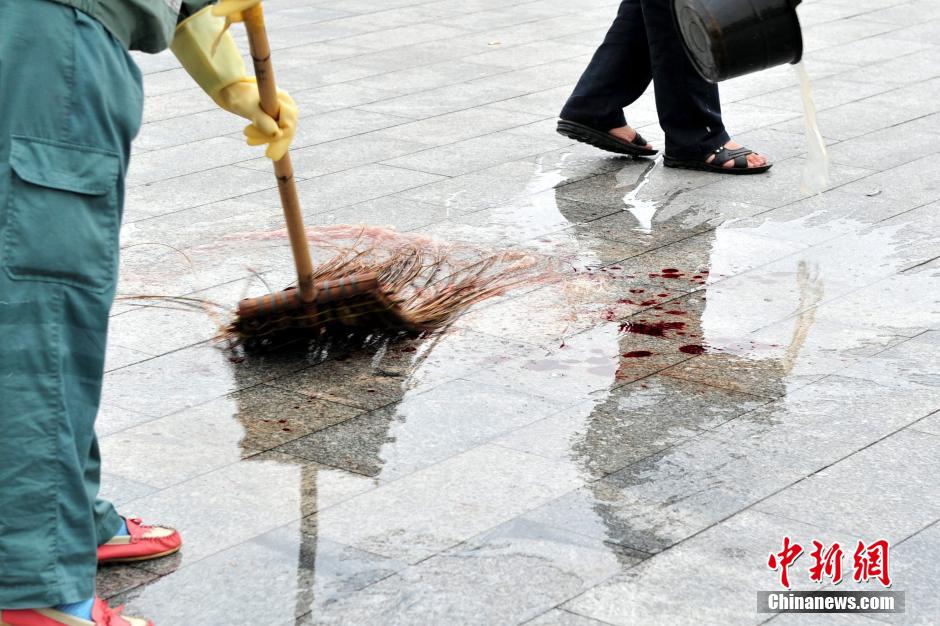 圖為環(huán)衛(wèi)工人在清理案發(fā)地點(diǎn)的血跡。