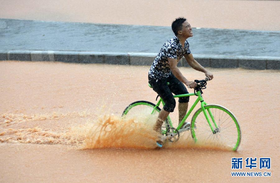 5月11日，一名行人在深圳街頭冒雨騎行。