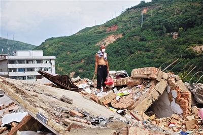 8月9日,龍頭山鎮(zhèn),一位老者在自家房屋廢墟上尋找家當。