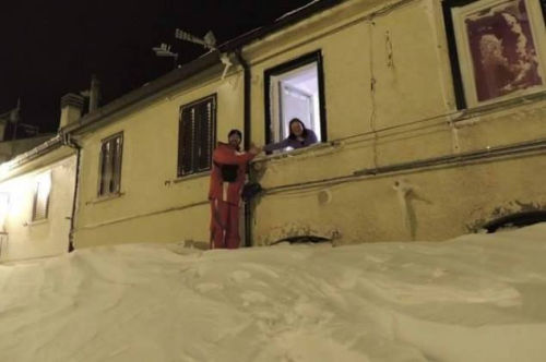 一個(gè)居民站在積雪上，可以與一名二樓鄰居在窗口握手。（來源：意大利氣象局）