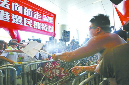 17日，在香港立法會外，一名反對政改的男子向支持派人群投擲標(biāo)牌。