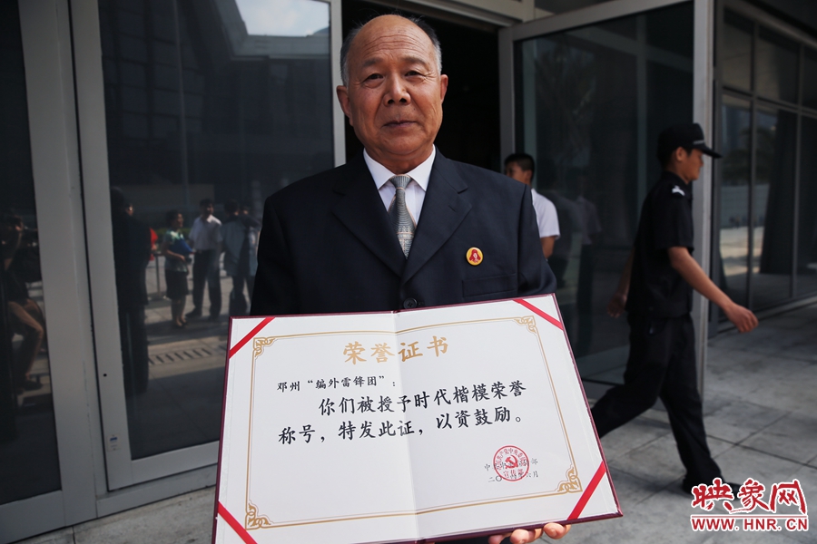 河南鄧州“編外雷鋒團”團長宋清梅向眾多記者展示中宣部授予的“時代楷模”榮譽證書。