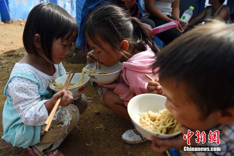 2014年8月6日，云南魯?shù)辇堫^山災(zāi)區(qū)，兒童在帳篷外吃飯。