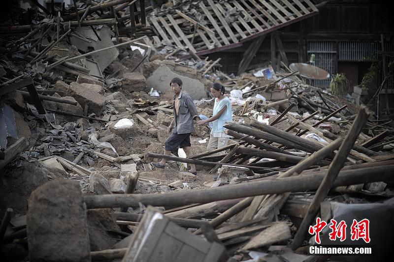 2014年8月5日，云南昭通龍頭山鎮(zhèn)老街，一對夫妻從居住房屋的廢墟中走過。