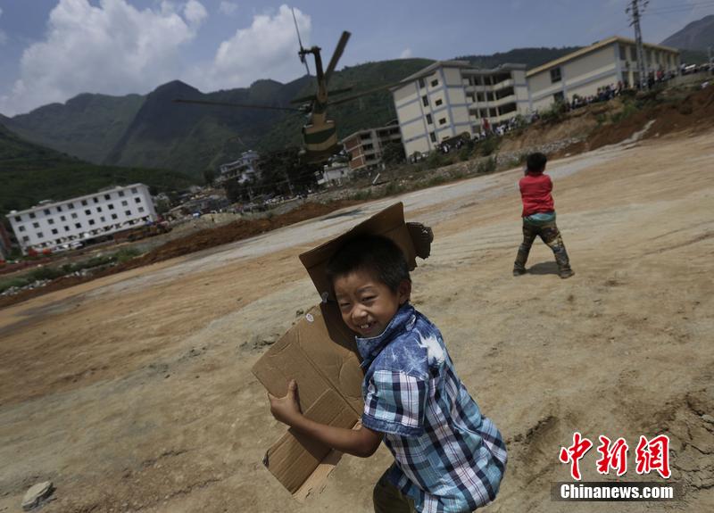 云南省昭通市魯?shù)榭h發(fā)生6.5級地震。幾個孩子在直升機降落的平地上玩耍。