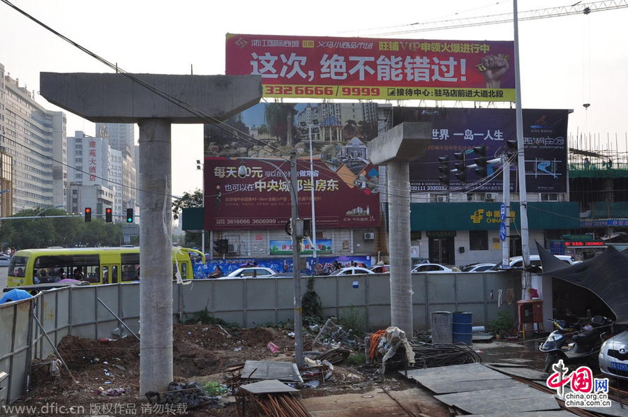 過街天橋一側(cè)的橋樁早已打好,可是對(duì)面的郵政銀行網(wǎng)點(diǎn)依舊在照常營(yíng)業(yè)。