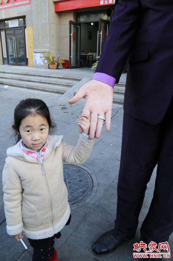 巨人“張歡”牽著一名漂亮的小女孩，兩人的手大小對比非常明顯。