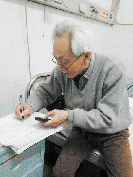 杜修源老人埋頭寫著特殊的“日記”。 李卓 攝